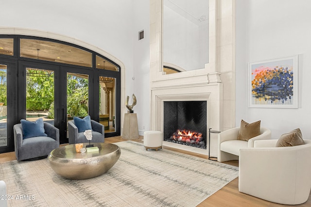 living room featuring a towering ceiling, hardwood / wood-style flooring, and french doors