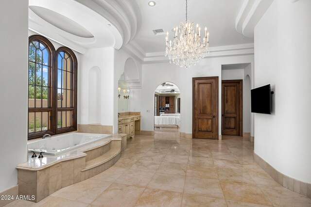 bathroom with a notable chandelier, vanity, and a relaxing tiled tub