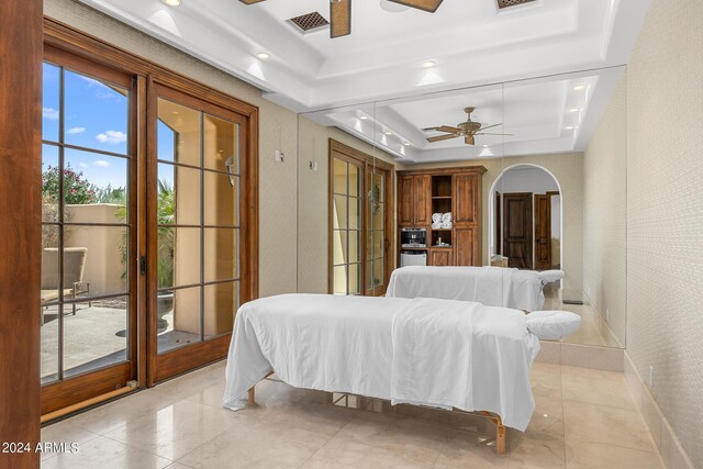 bedroom featuring a raised ceiling, light tile patterned flooring, access to outside, and ceiling fan