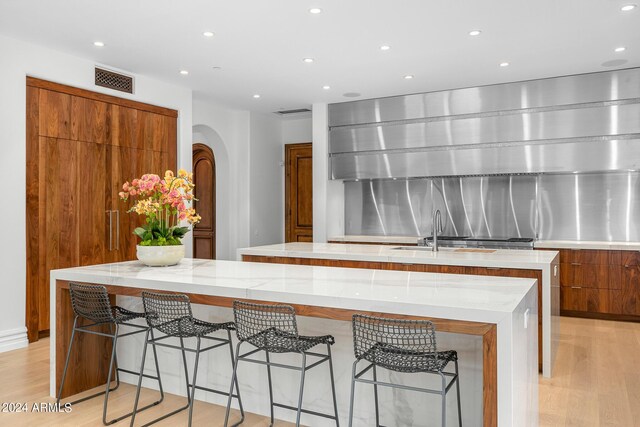 kitchen with a large island, light hardwood / wood-style floors, and a kitchen bar