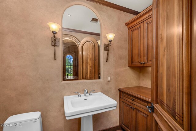 bathroom featuring sink, crown molding, and toilet