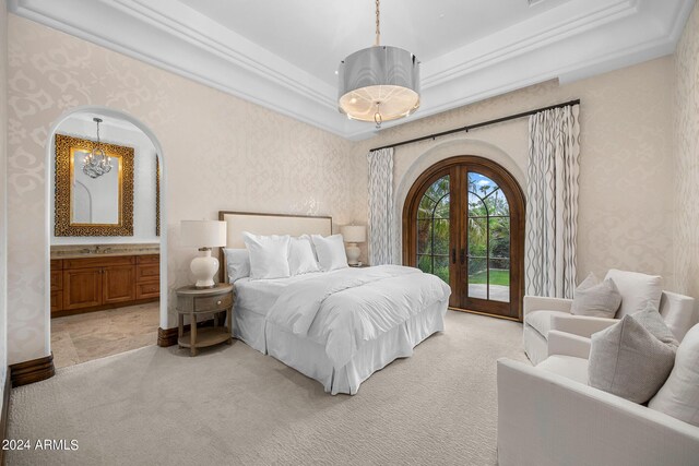 carpeted bedroom featuring access to exterior, sink, a raised ceiling, ornamental molding, and french doors