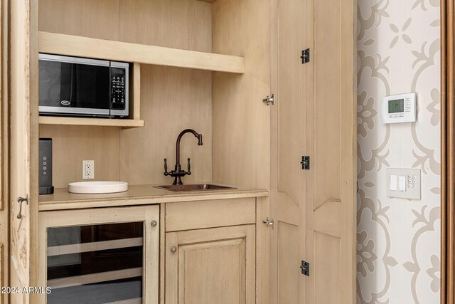 bar with light brown cabinetry, beverage cooler, and sink