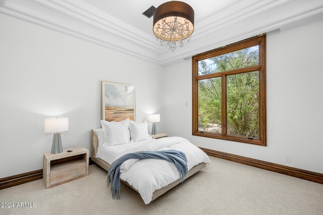 carpeted bedroom featuring a raised ceiling, ornamental molding, and a notable chandelier