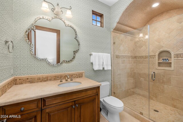 bathroom featuring a shower with door, vanity, and toilet