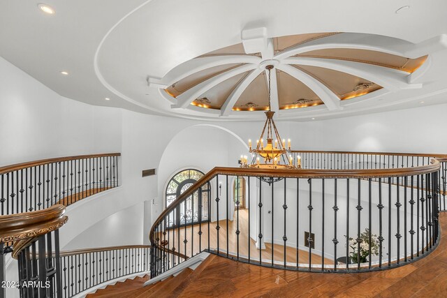 stairs with wood-type flooring and a notable chandelier