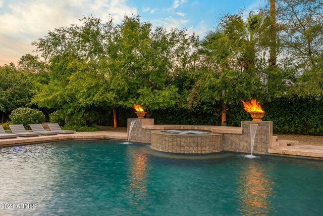 view of swimming pool with pool water feature and an in ground hot tub