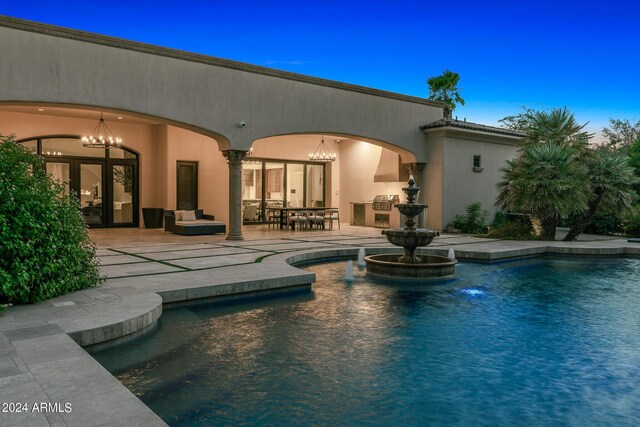 pool at dusk with an outdoor living space and a patio area