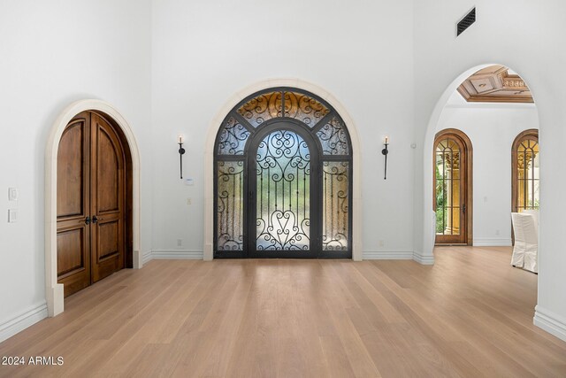 foyer entrance with light hardwood / wood-style flooring and a towering ceiling