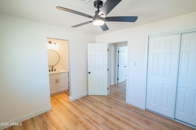 unfurnished bedroom featuring ensuite bathroom, sink, a closet, light hardwood / wood-style floors, and ceiling fan