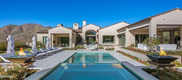 view of pool with a fire pit, a mountain view, and a patio