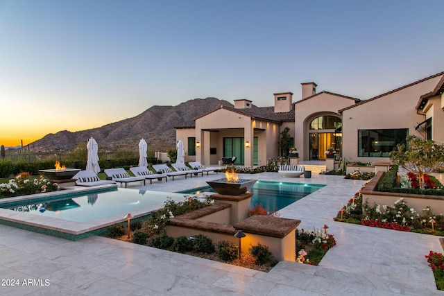 pool at dusk with a patio area and a mountain view