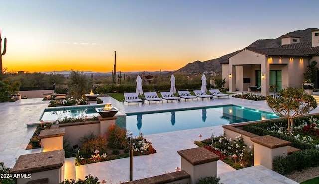 pool at dusk with a patio and a mountain view