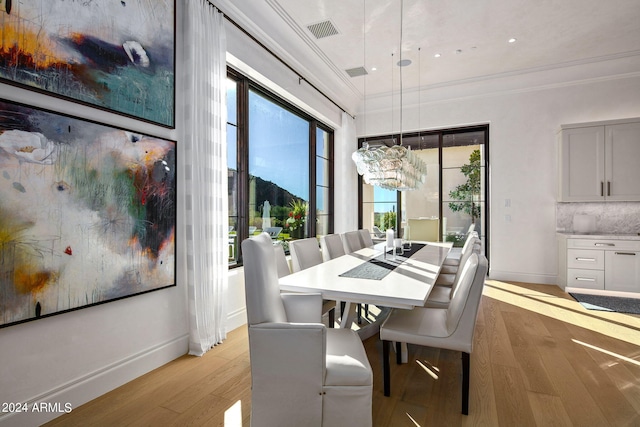 dining space featuring ornamental molding and light hardwood / wood-style floors