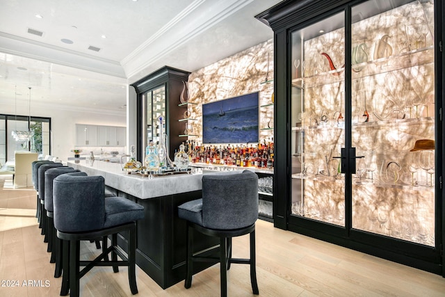 bar featuring ornamental molding, pendant lighting, and light wood-type flooring