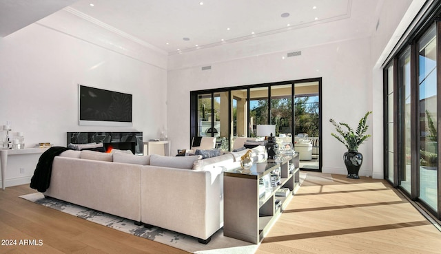 living room with light wood-type flooring, a high end fireplace, and a high ceiling