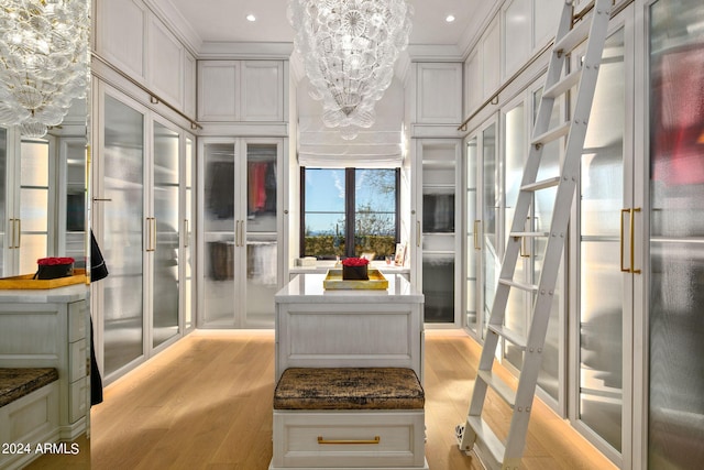 interior space with a center island, light hardwood / wood-style floors, white cabinetry, crown molding, and an inviting chandelier