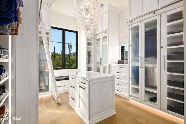 walk in closet featuring light hardwood / wood-style flooring and an inviting chandelier