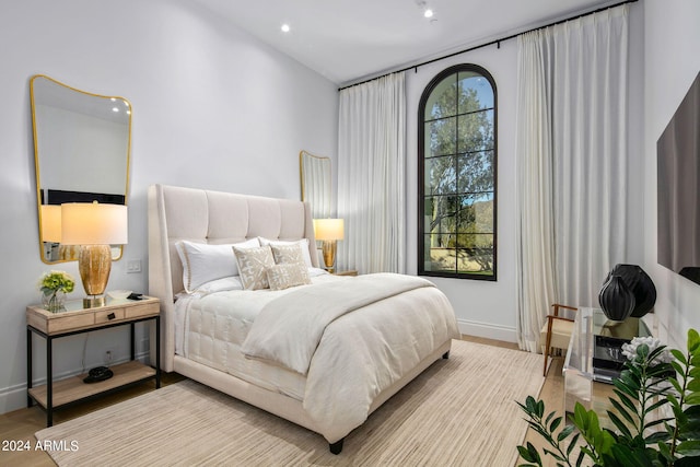 bedroom featuring lofted ceiling, multiple windows, and light wood-type flooring