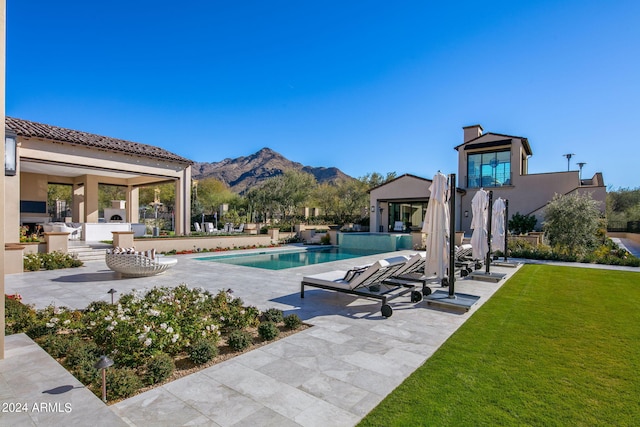 view of swimming pool featuring a patio area, a mountain view, and a yard