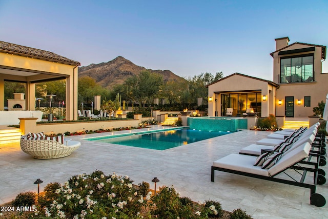 pool at dusk featuring a patio area and a mountain view