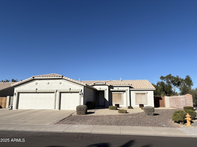 view of front facade featuring a tile roof, stucco siding, fence, a garage, and driveway