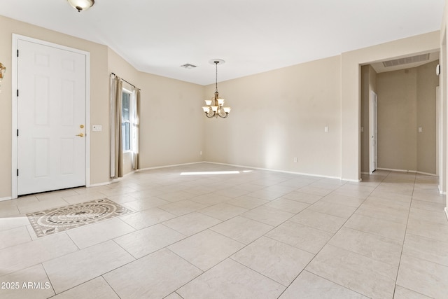 empty room with light tile patterned flooring and a notable chandelier