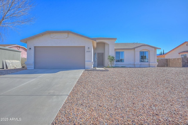 view of front of home featuring stucco siding, an attached garage, driveway, and fence