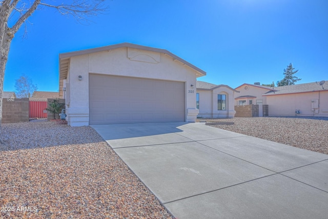 view of front of home with an attached garage, fence, driveway, and stucco siding