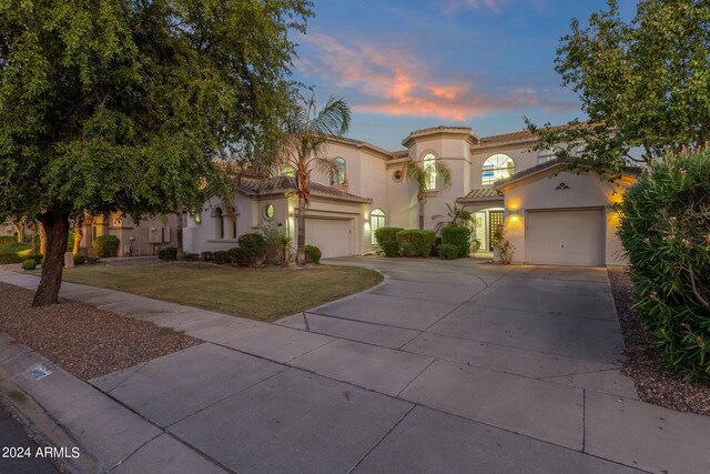 mediterranean / spanish-style house featuring a garage and a yard