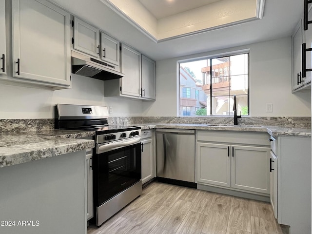 kitchen featuring light stone counters, light hardwood / wood-style floors, sink, and stainless steel appliances