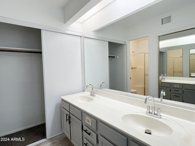 bathroom featuring wood-type flooring, vanity, toilet, and walk in shower