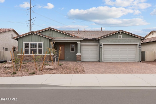 12311 W Parkway Ln, Avondale, AZ 85323 - view of front of home featuring decorative driveway, fence, a garage, a tiled roof, and stone siding