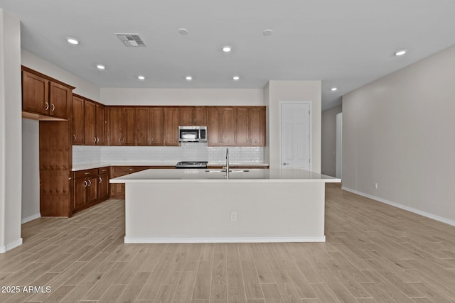 12311 W Parkway Ln, Avondale, AZ 85323 - kitchen with appliances with stainless steel finishes, light countertops, a center island with sink, tasteful backsplash, and recessed lighting