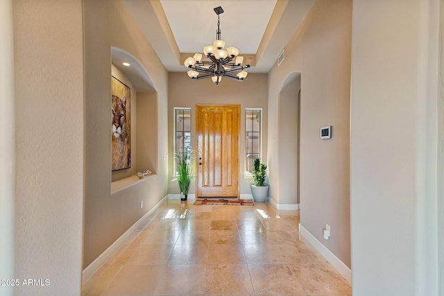 entrance foyer with a raised ceiling and an inviting chandelier