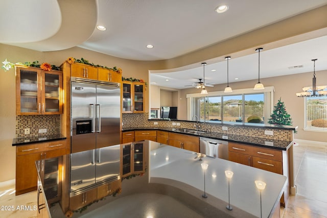 kitchen featuring sink, hanging light fixtures, backsplash, kitchen peninsula, and appliances with stainless steel finishes