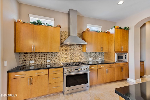 kitchen with decorative backsplash, appliances with stainless steel finishes, plenty of natural light, and wall chimney range hood