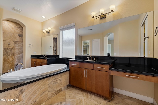 bathroom featuring vanity and a relaxing tiled tub