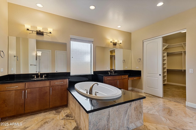 bathroom featuring tiled tub and vanity