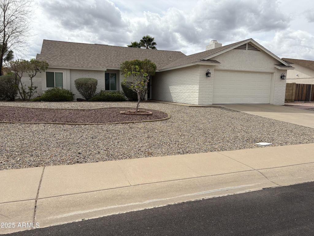 single story home featuring brick siding, an attached garage, a shingled roof, a chimney, and driveway