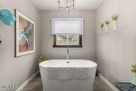 bathroom with baseboards, a freestanding bath, and a chandelier