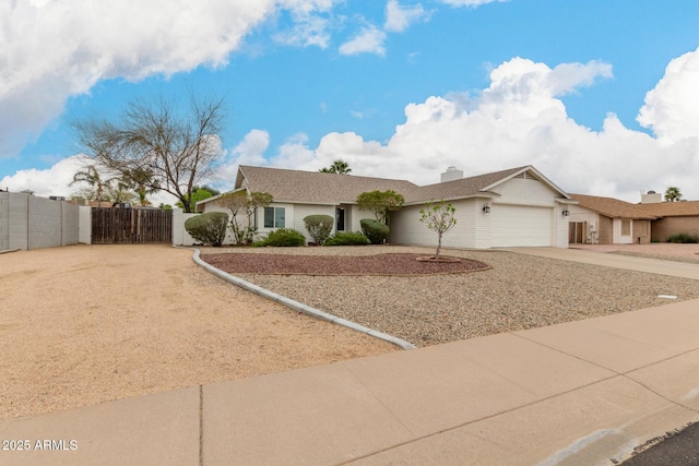 ranch-style home featuring a gate, fence, an attached garage, a chimney, and concrete driveway