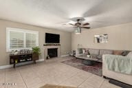 living room featuring tile patterned floors, a fireplace, baseboards, and ceiling fan