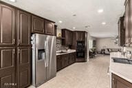 kitchen with recessed lighting, dark brown cabinets, stainless steel fridge, and light countertops