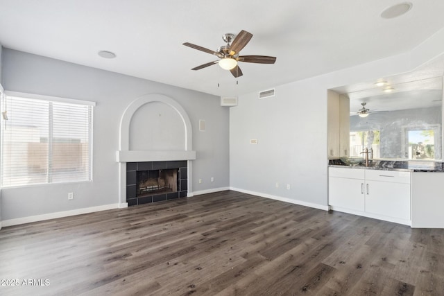 3641 E Park Ave, Phoenix, AZ 85044 - unfurnished living room featuring ceiling fan, dark wood-style floors, a tiled fireplace, and baseboards