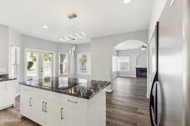3641 E Park Ave, Phoenix, AZ 85044 - kitchen with freestanding refrigerator, a tiled fireplace, wood finished floors, arched walkways, and white cabinets