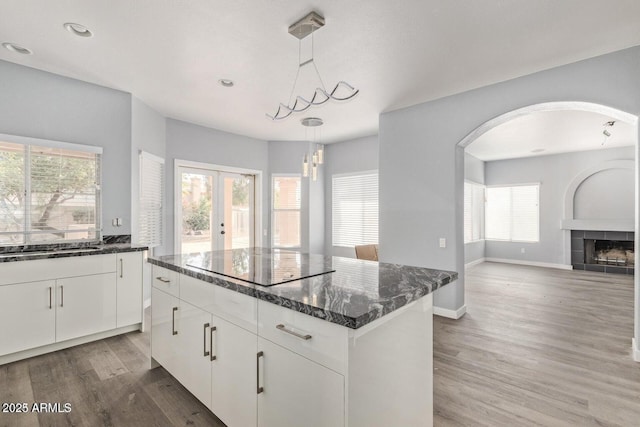 3641 E Park Ave, Phoenix, AZ 85044 - kitchen with arched walkways, wood finished floors, dark stone countertops, hanging light fixtures, and white cabinets