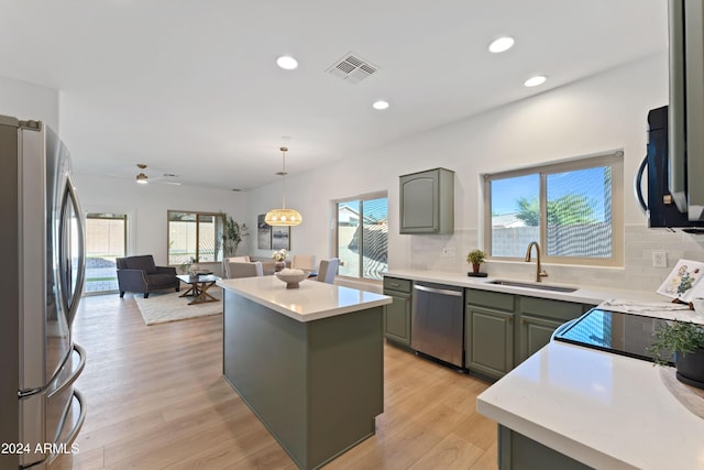 kitchen featuring decorative backsplash, appliances with stainless steel finishes, light wood-type flooring, sink, and a kitchen island