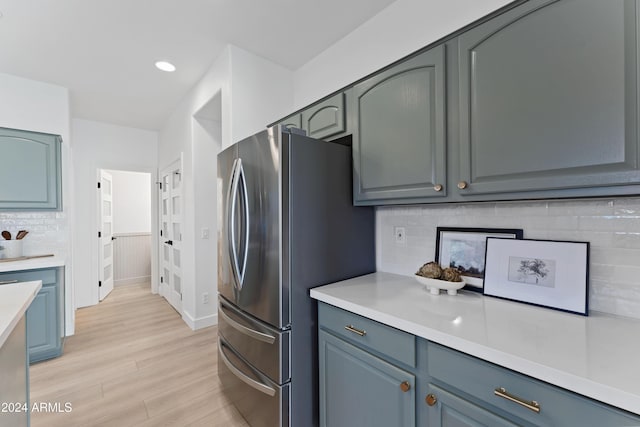 kitchen with backsplash, stainless steel refrigerator, and light hardwood / wood-style flooring