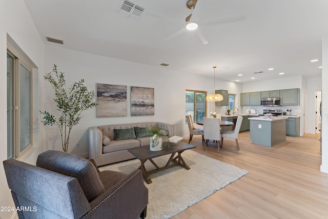 living room with light hardwood / wood-style floors, ceiling fan, and sink